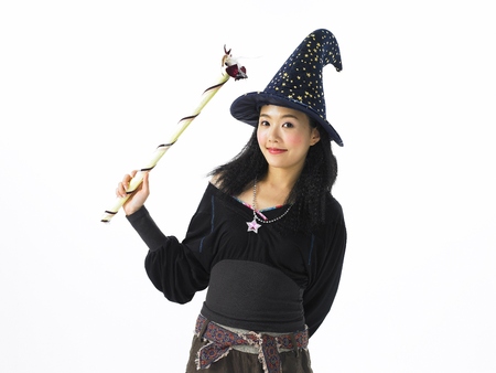 Asian woman fashion model posing in a studio as wearing pants outfit with witch hatの写真素材