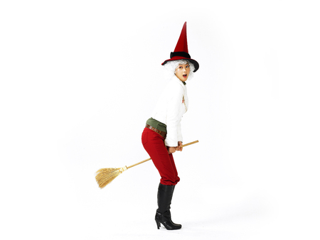 Young Asian female fashion model posing in a studio wearing winter outfit with witch hat and broomの写真素材