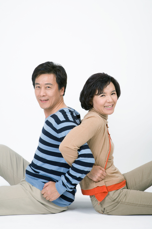 Mid-aged married couple posing in a studio as sitting on floorの写真素材