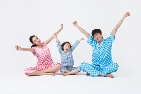 Parents and young kids spending family time together stretching in pajamasの写真素材