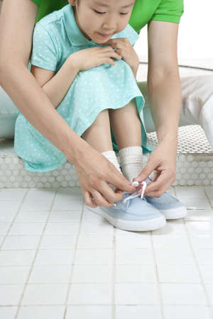 Father and daughter spending family time together as teaching how to tie shoe laceの写真素材