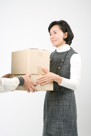 Mid-aged Asian woman posing in a studio with delivery boxesの写真素材