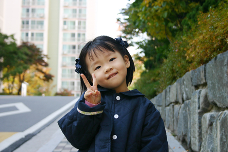 Little Asian young girl posing with v hand in the streetの写真素材