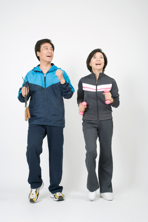 Mid-aged married couple posing in a studio as working out in training outfitsの写真素材