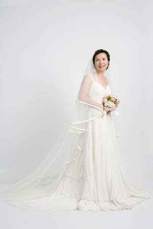 Mid-aged Asian woman posing in a studio as wearing wedding dressesの写真素材