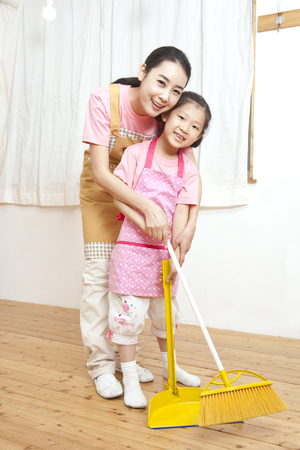 Mother and daughter spending family time as cleaning with brooms togetherの写真素材