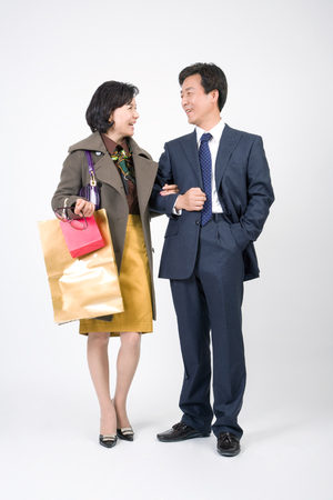Mid-aged married couple posing in a studio as walking in the street with shopping bagsの写真素材