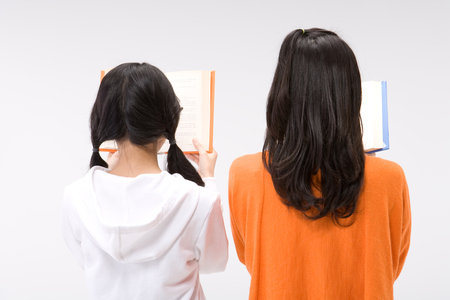 Two young Asian women posing with books - isolated on whiteの写真素材