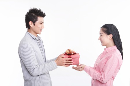 Young Asian couple posing with a gift box in the studio - isolated on white