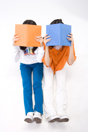Two young Asian women posing with books - isolated on whiteの写真素材