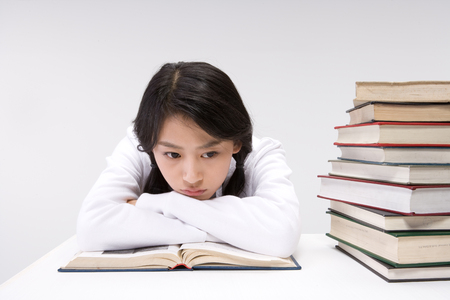 Asian female student looking worried with books around her - isolated on whiteの写真素材