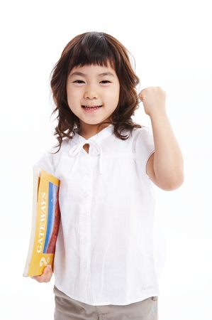 Little Asian girl holding books with cheerful pose - isolated on whiteの写真素材