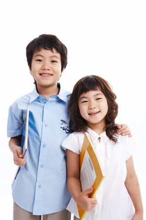 Little Asian boy and girl posing, holding books in their arms - isolated on whiteの写真素材