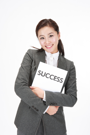 Asian business woman posing with a piece of paper that has SUCCESS on it - isolated on whiteの写真素材