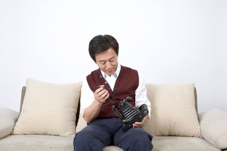 Asian middle aged man looking at an old camera - isolated on white