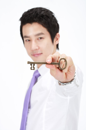 Asian businessman posing with a key - isolated on whiteの写真素材