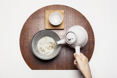 Hand pouring tea from a teapot - isolated on whiteの写真素材