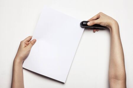 Hand stapling paper with a stapler - isolated on whiteの写真素材