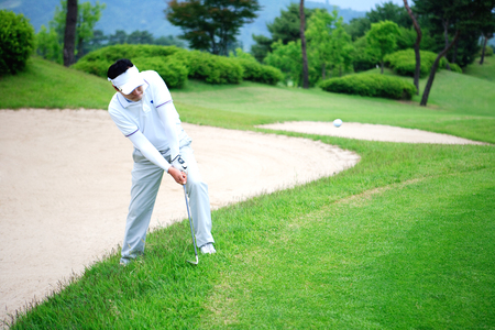 Golf shot from sand bunker male golfer hitting ballの写真素材