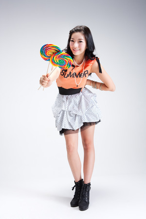 Cute Asian Woman holding sticky lollipop isolated on whiteの写真素材