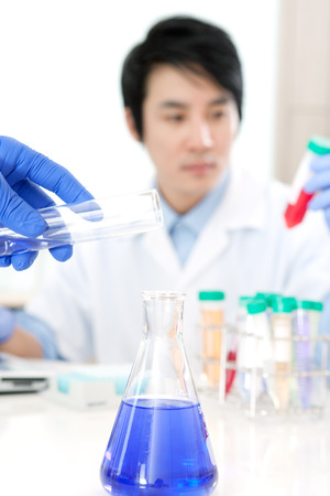 Blurred scientist in laboratory with focus on flaskの写真素材