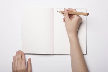 Hand writing with a pencil on a blank notebook - isolated on whiteの写真素材