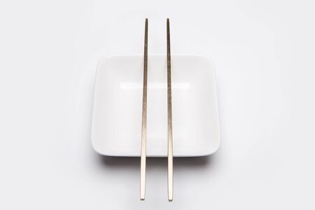Wooden chopsticks on small white plate - isolated on whiteの写真素材