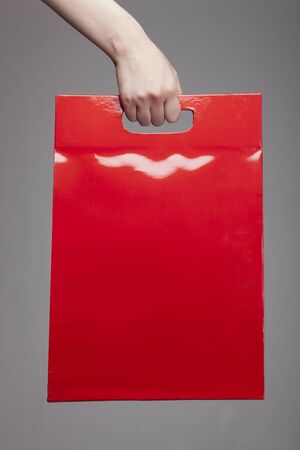 Hand holding a red luxury gift bag - isolated on whiteの写真素材