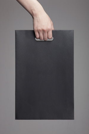 Hand holding a black luxury gift bag - isolated on whiteの写真素材
