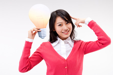 Asian young woman thinking with bulb model isolated on whiteの写真素材