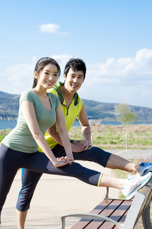 Asian sporty couple doing stretching exercises outdoorの写真素材