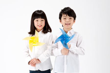Asian boy and girl with pinwheel isolated on whiteの写真素材