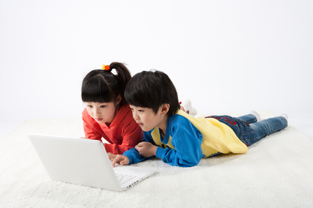 Asian boy and girl using laptop isolated on whiteの写真素材