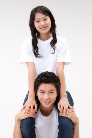 Asian young woman riding on friend's shoulders isolated on whiteの写真素材