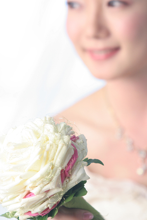 Blurred Asian beautiful bride focus on flowerの写真素材