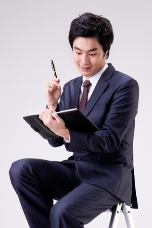 Close up Asian business man looking at note isolated on whiteの写真素材