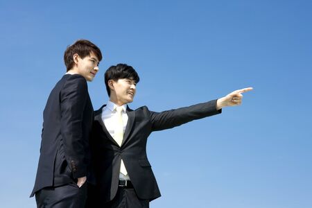 Asian two business men pointing something with skyの写真素材