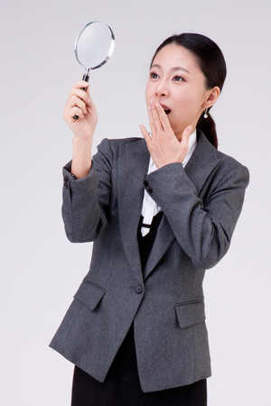 Close up Asian business woman with magnifier isolated on whiteの写真素材