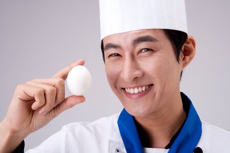 Close up Asian man chef with egg isolated on whiteの写真素材