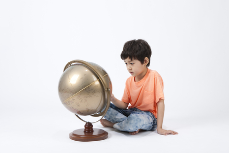 Asian cute boy playing with globe isolated on whiteの写真素材