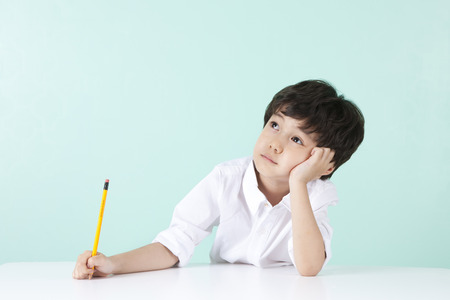 Asian cute boy thinking gesture with pencil on mint backgroundの写真素材