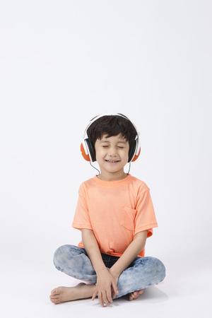 Asian cute boy listening music on floor isolated on whiteの写真素材