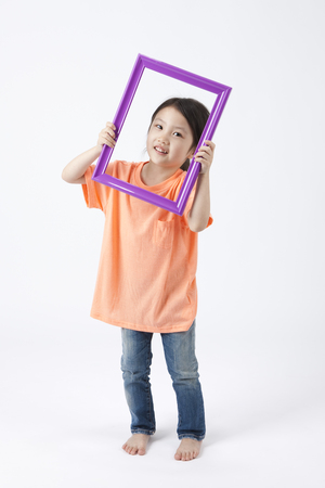 Asian cute girl with photo frame while smiling isolated on whiteの写真素材