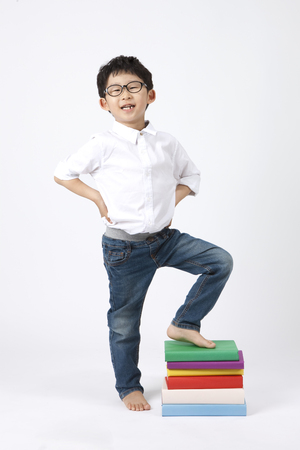 Asian smart boy looking happy with pile of books isolated on whiteの写真素材