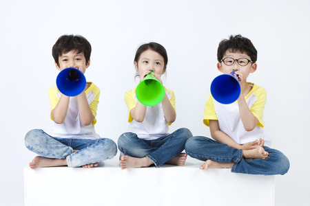 Asian cute children having fun with loudspeaker isolated on whiteの写真素材