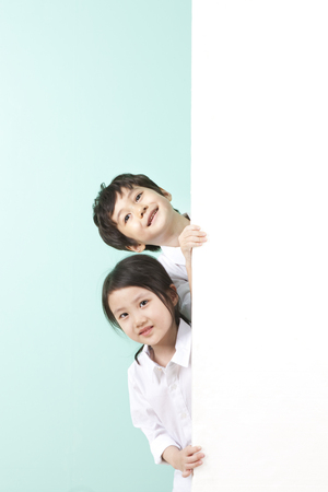 Asian cute boy and girl with white board on mint backgroundの写真素材