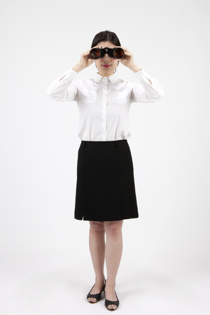 Asian business woman looking through a telescope isolated on whiteの写真素材