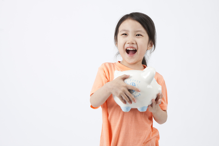 Close up Asian cute girl holding piggy bank isolated on whiteの写真素材