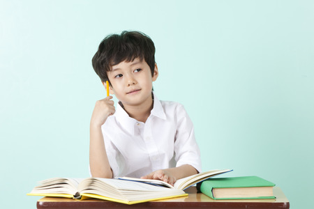 Asian cute boy thinking gesture with pencil on mint backgroundの写真素材