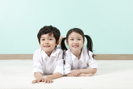 Asian cute boy and girl lying on the floor with smileの写真素材